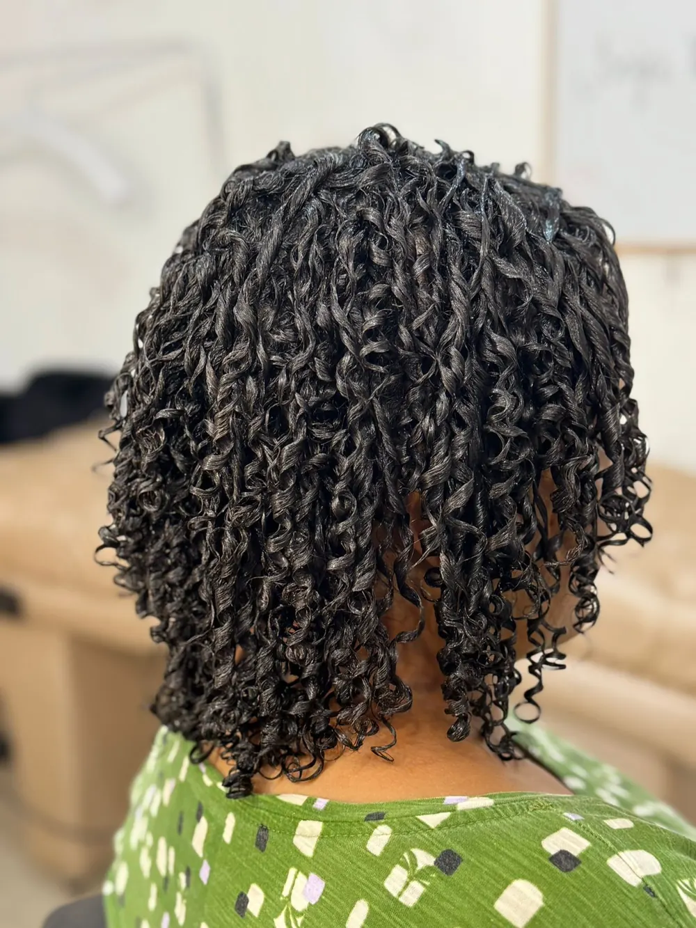 Cabelo curto com cachos pequenos, definidos e brilhantes, visto de costas no salão
