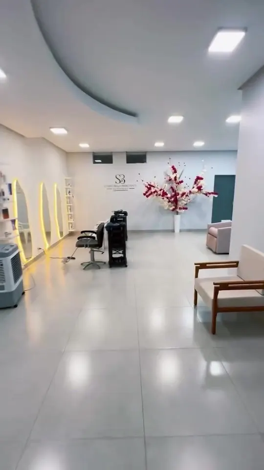 Interior do salão: piso claro, estações com espelhos iluminados e o arranjo de flores ao fundo
