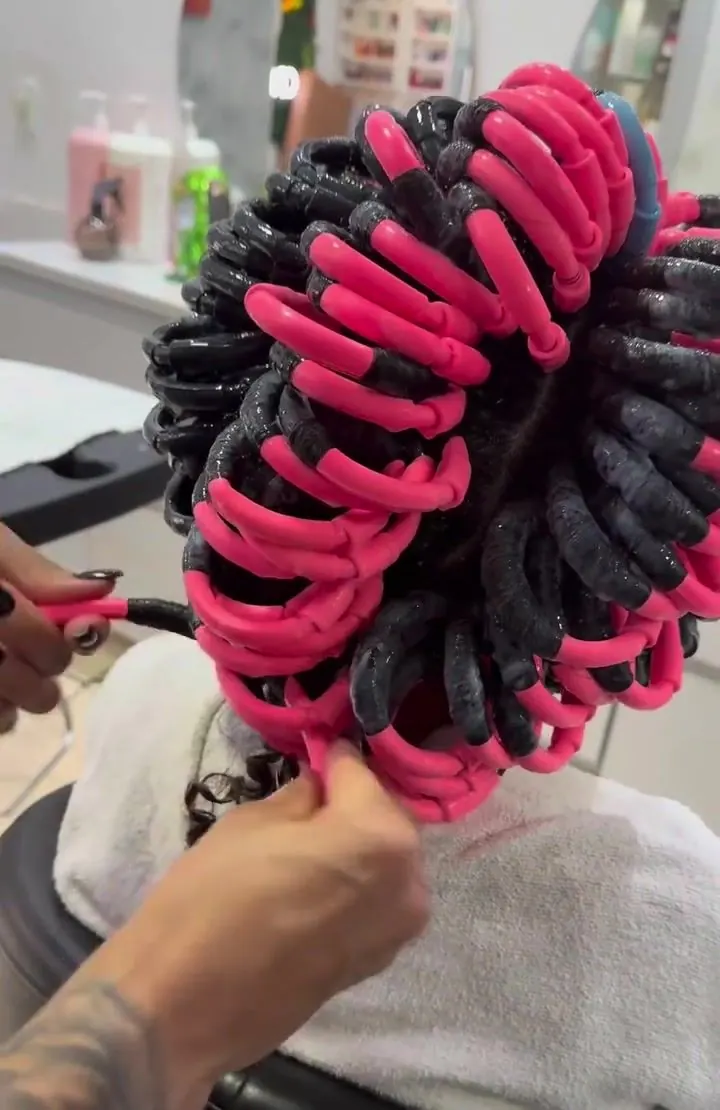 Cabelo enrolado em bobes flexíveis rosa e pretos durante o Efeito Caracóis, visto de trás