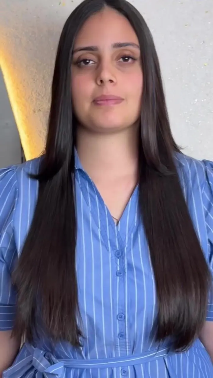 Cliente de vestido azul listrado com cabelo preto, liso e longo até a cintura
