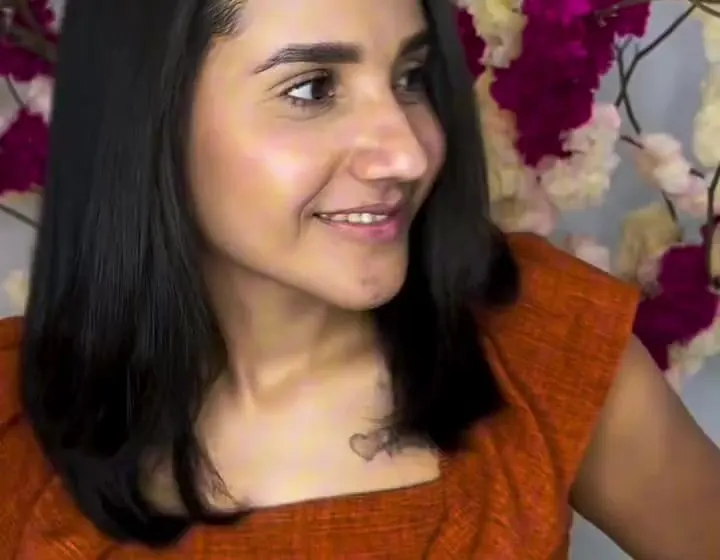 Cliente sorrindo de perfil com cabelo preto liso na altura dos ombros, depois do Liso Impactante
