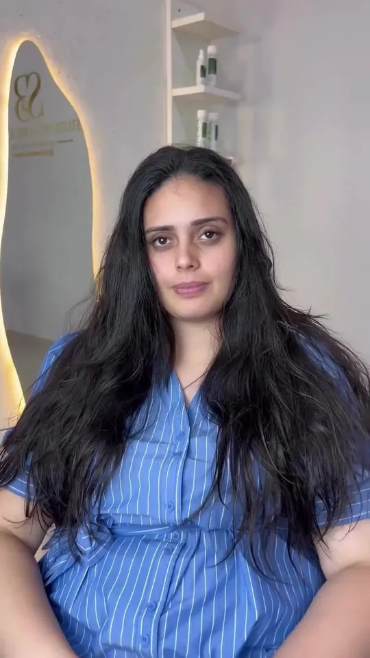 Cliente de vestido azul mostrando o cabelo longo, liso e brilhante depois do Liso Impactante