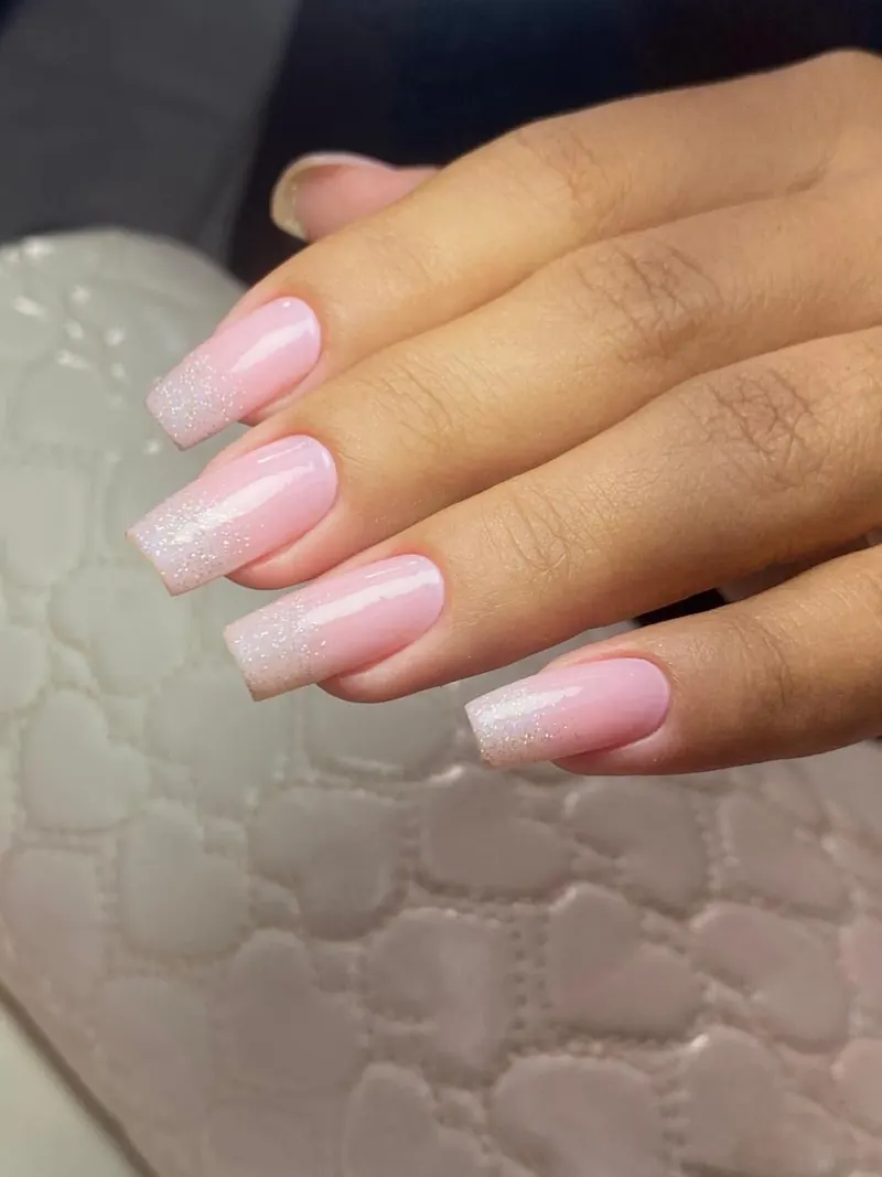 Unhas amendoadas brancas com francesinha, uma delas com glitter prateado e fio de strass